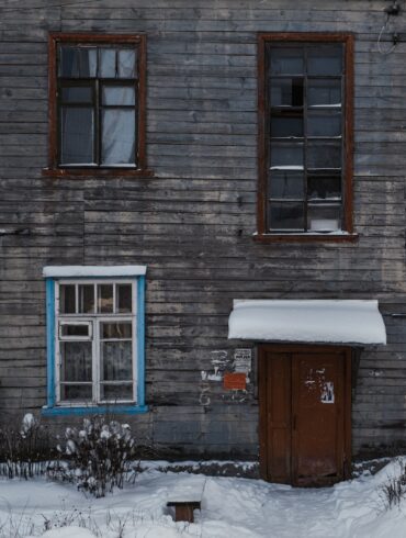 brown brick house with snow covered field