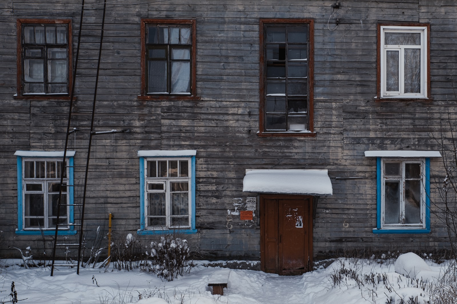 brown brick house with snow covered field