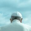 person wearing white cap looking down under cloudy sky during daytime