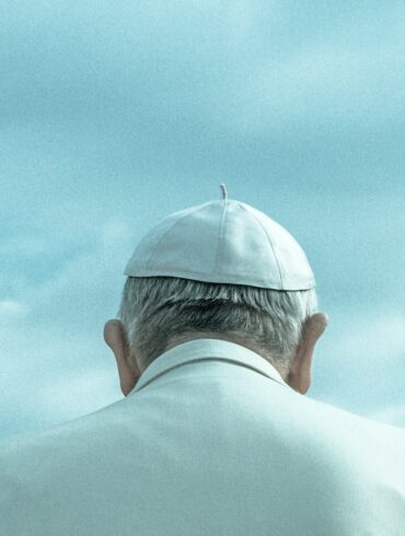 person wearing white cap looking down under cloudy sky during daytime