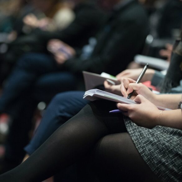 selective focus photography of people sitting on chairs while writing on notebooks