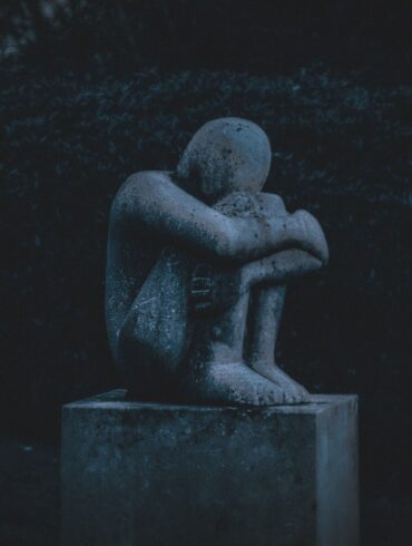 man hugging his knee statue