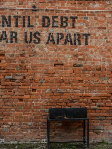 Until debt tear us apart printed red brick wall at daytime
