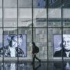 person wearing hoodie walking beside portrait of two women