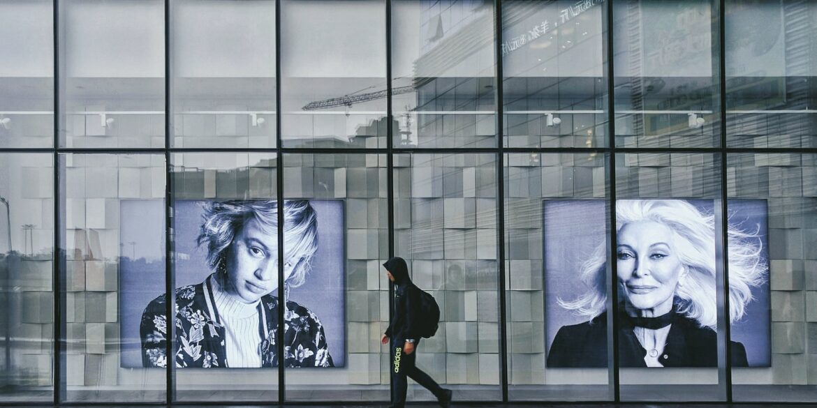 person wearing hoodie walking beside portrait of two women