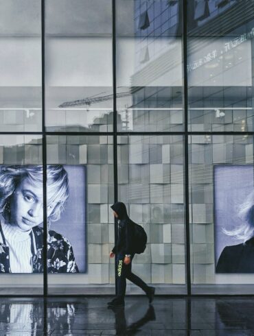 person wearing hoodie walking beside portrait of two women