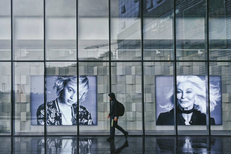 person wearing hoodie walking beside portrait of two women