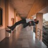 man in black jacket and black pants jumping on brown wooden floor