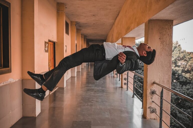 man in black jacket and black pants jumping on brown wooden floor