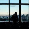 silhouette of person looking to glass window