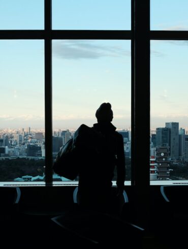 silhouette of person looking to glass window