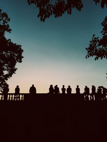 silhouette of people standing beside bridge during blue hour