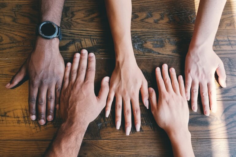 five human hands on brown surface