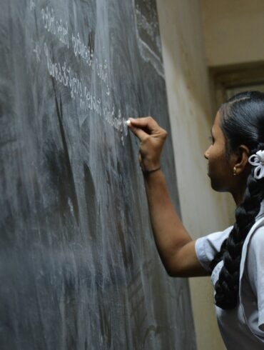 woman standing writing on black chalkboard