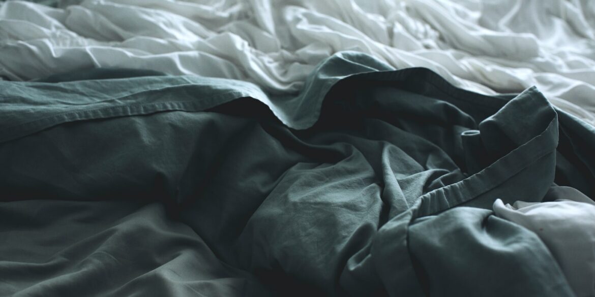 gray apparel beside white sheet