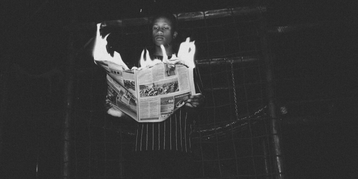 man holding burning newspaper