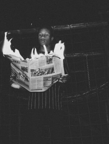 man holding burning newspaper