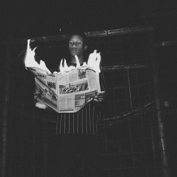 man holding burning newspaper