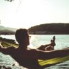 silhouette of woman sitting on hammock by the sea during daytime