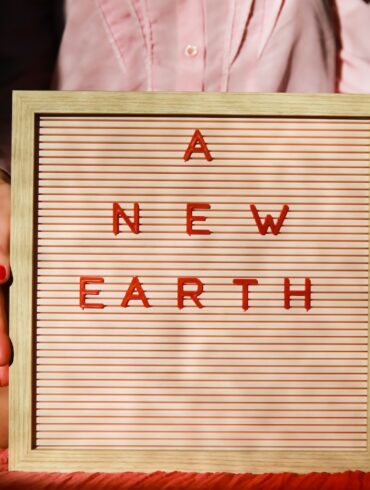 a woman holding a sign that says a new earth