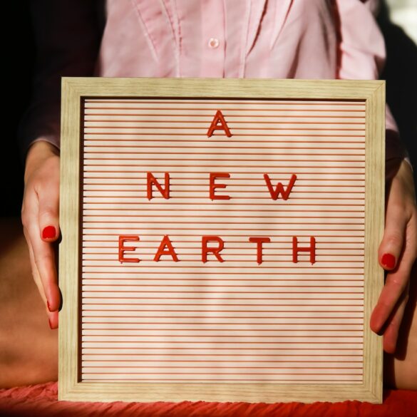 a woman holding a sign that says a new earth