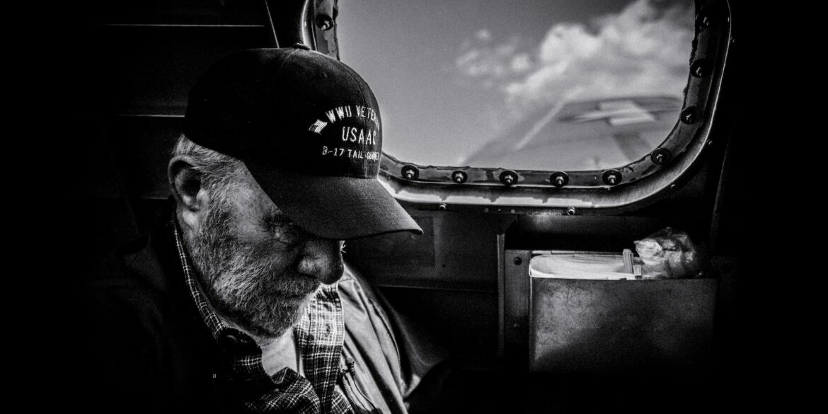 grayscale photo of man in plaid shirt and cap looking at the sky