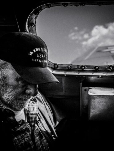 grayscale photo of man in plaid shirt and cap looking at the sky