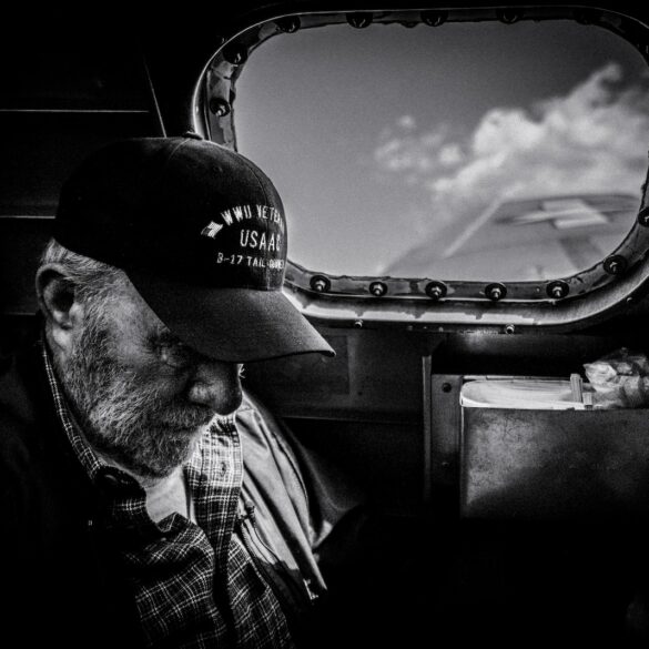 grayscale photo of man in plaid shirt and cap looking at the sky