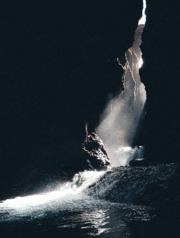 a large rock sticking out of a body of water