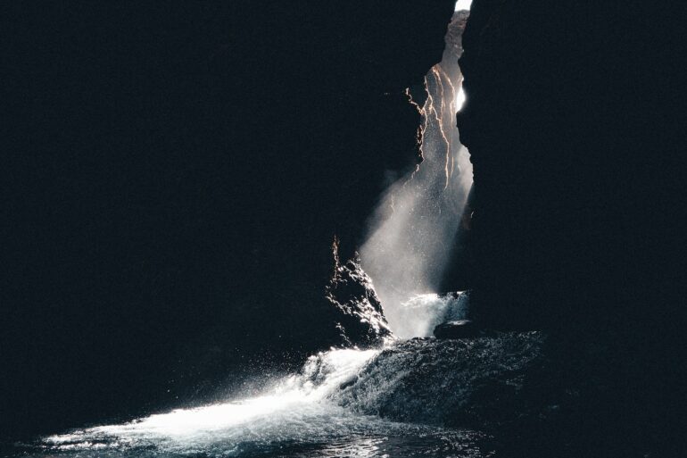 a large rock sticking out of a body of water