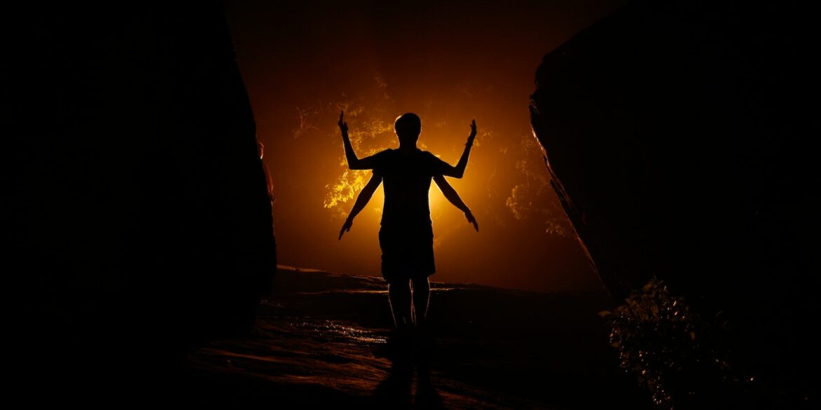 a person standing in the dark with their arms outstretched