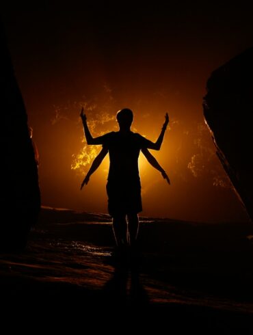 a person standing in the dark with their arms outstretched