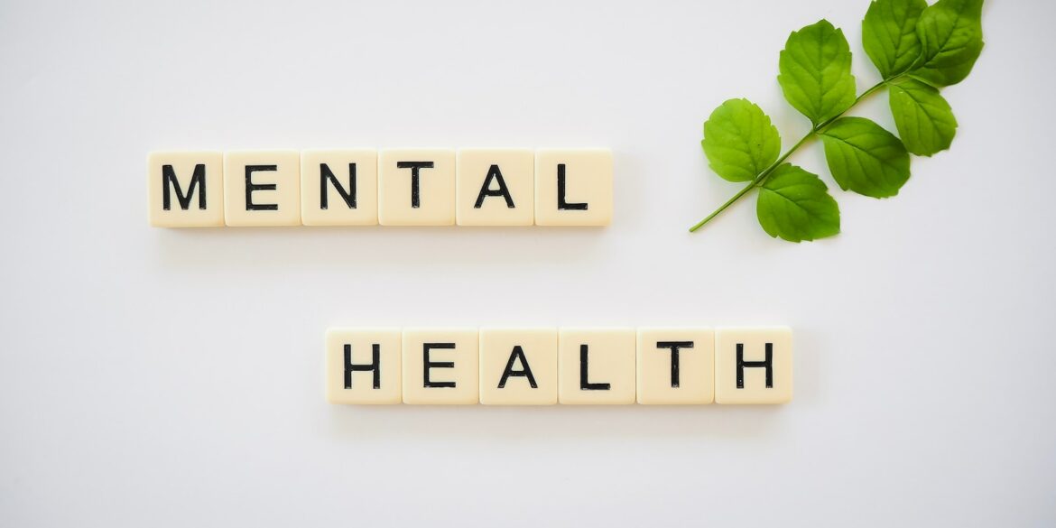 the word mental health spelled with scrabbles next to a green leaf