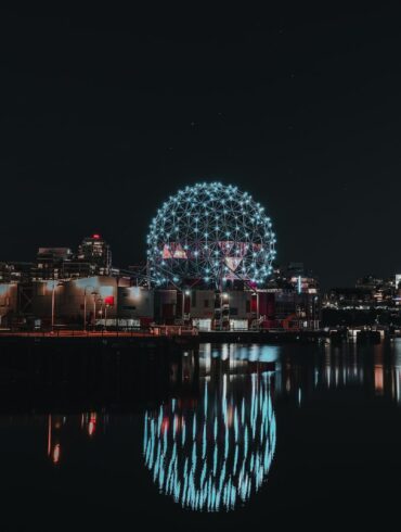 blue and white lighted ferris wheel near body of water during night time