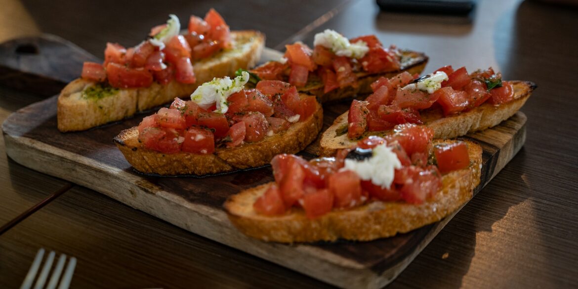 brown bread with tomato and green vegetable on brown wooden table