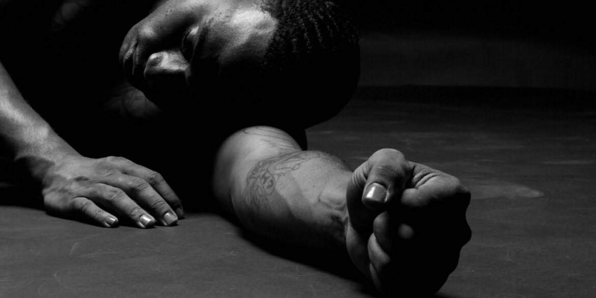 a man laying on the ground with his hands on his knees