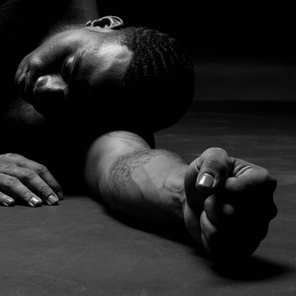 a man laying on the ground with his hands on his knees