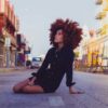 woman in black long sleeve shirt sitting on sidewalk during daytime