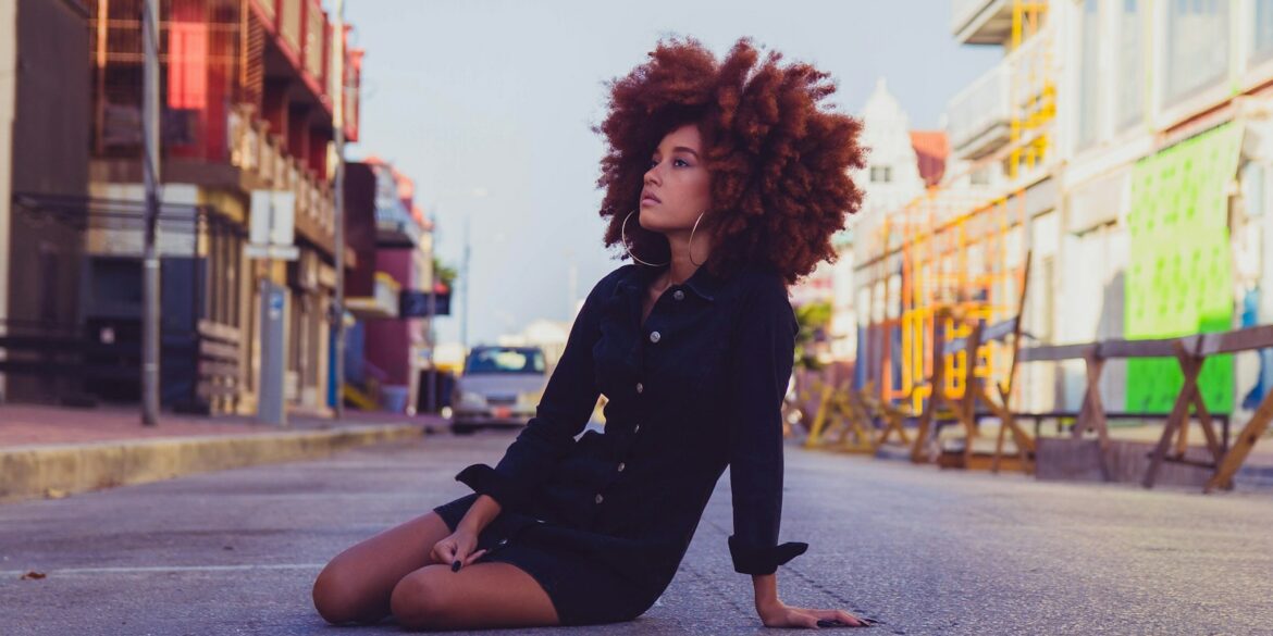 woman in black long sleeve shirt sitting on sidewalk during daytime