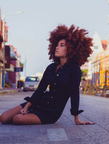 woman in black long sleeve shirt sitting on sidewalk during daytime