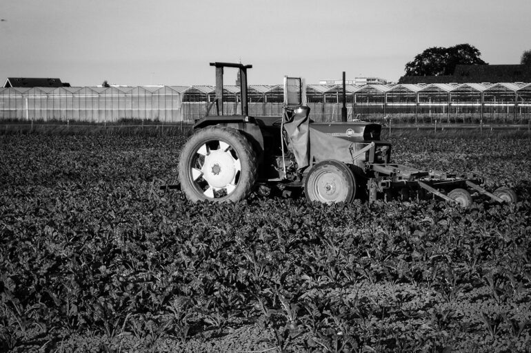 grayscale photo of tractor on grass field