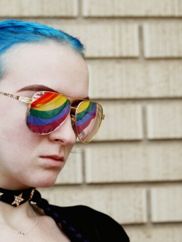 a woman with blue hair and rainbow glasses