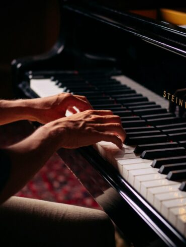 person playing black upright piano