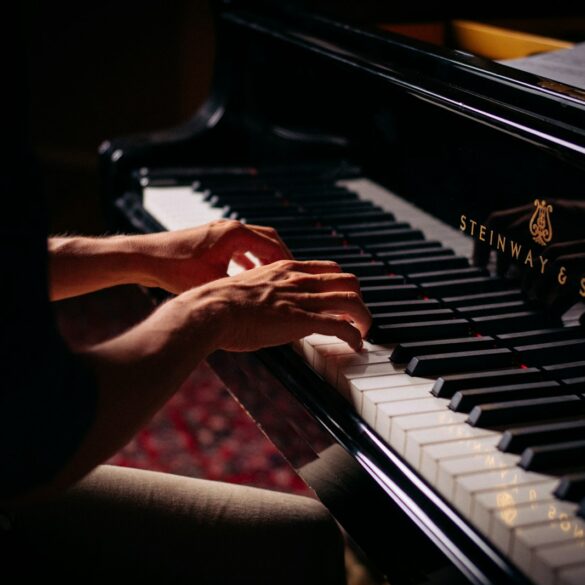 person playing black upright piano
