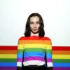 a woman standing in front of a rainbow colored wall