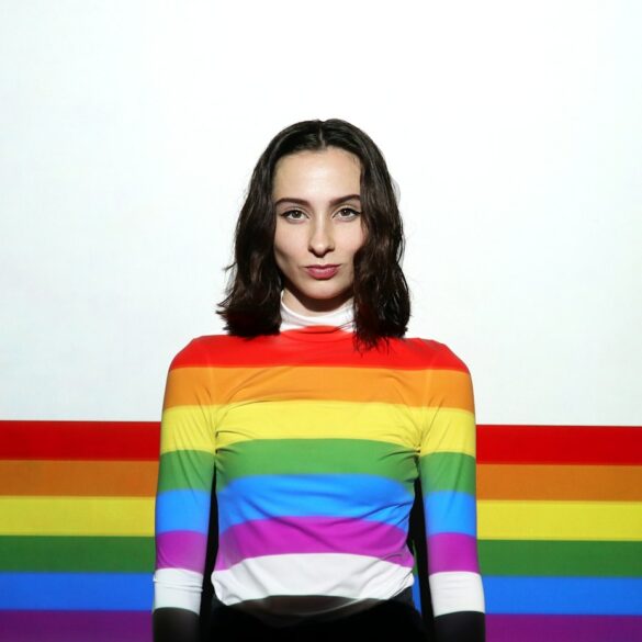 a woman standing in front of a rainbow colored wall