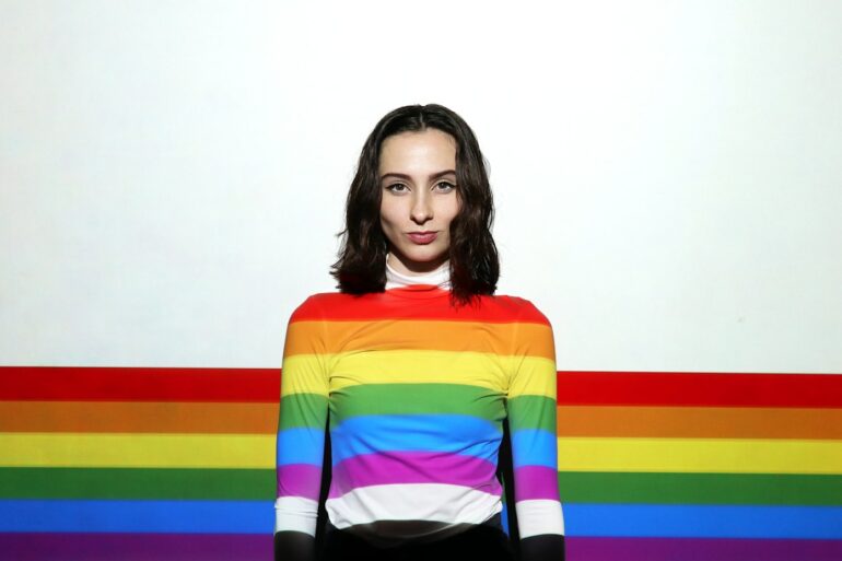 a woman standing in front of a rainbow colored wall