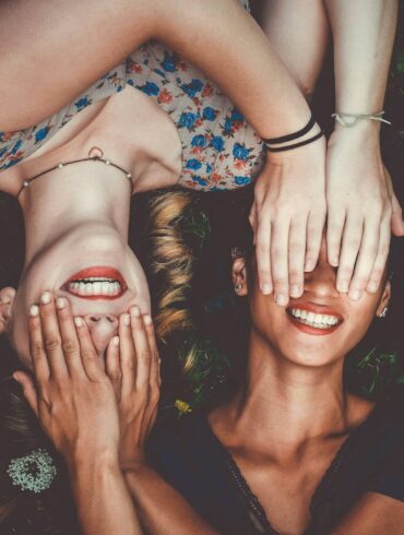 man and woman smiling while laying on lawn field