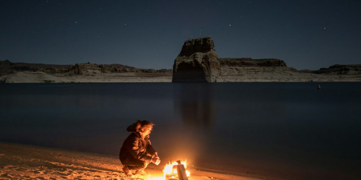 person sitting beside bonfire on seashore