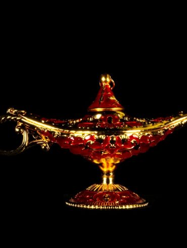 A red and gold teapot with smoke coming out of it
